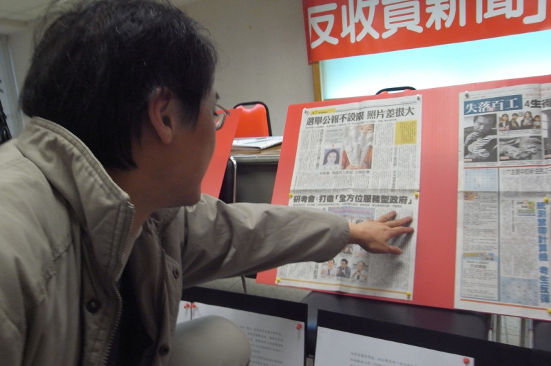 記協會長楊偉中指著報紙版面上的新聞，表示很多政府都會花錢購買新聞。圖片來源：楊宗興/攝   