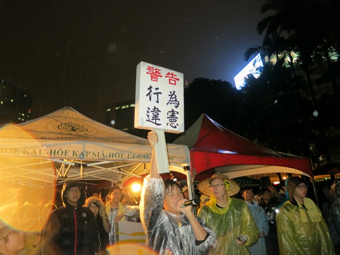 對於警方舉牌警告，反對媒體怪獸學生們26日晚間在行政院也以「行為違憲」牌子回敬。圖：林朝億/攝   