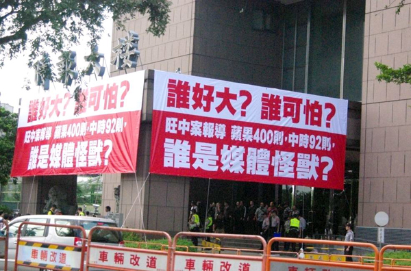 中時人員剛才於時報大樓門口高掛起3面布條，上頭寫著「誰好大？誰可怕？」，並以數據指出「旺中案報導，蘋果400則，中時92則」，質疑「誰是媒體怪獸？」嗆聲意味濃。圖片來源：林靖堂/攝   