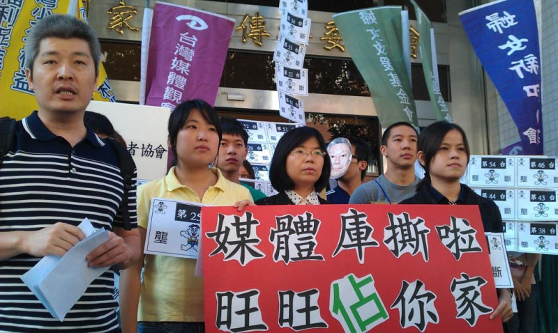 民間團體高舉著「媒體庫撕啦，旺旺在你家」、「旺旺壟斷」等標語，並以行動劇與齊唱改編後的「旺旺之歌」作為抗議。圖片來源:李雲深攝影   