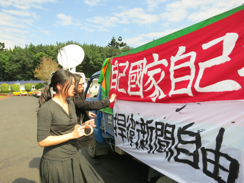 反媒體巨獸青年聯盟學生們21日在台北市自由廣場上，將貨車旁宣傳布條拉緊，做最後的準備工作。圖：林朝億/攝   
