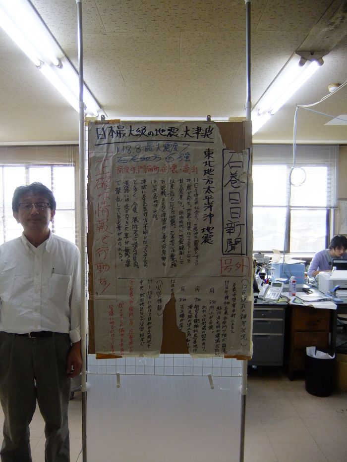 《石卷日日新聞》報導部長武內宏之站在第一枚壁報(2011年3月12日號外)旁邊。圖：安德毅攝   