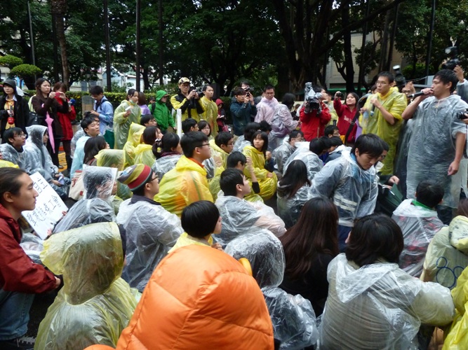「反媒體巨獸青年聯盟」學生在政院大門口淋雨靜坐。圖：謝莉慧/攝   