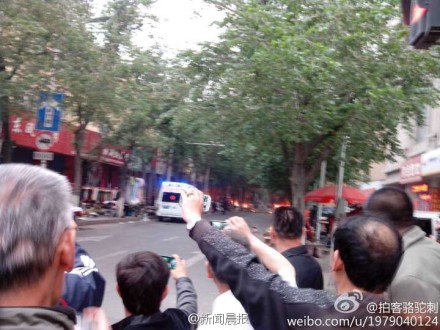 新疆烏魯木齊市一處早市，22日上午7時50分左右發生爆炸案，現場烈焰濃煙四起，救護車趕到現場準備急救傷患。圖：翻攝自網友「拍客駱駝刺」微博   