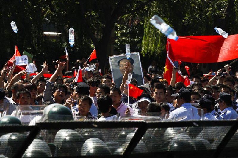 北京地區的示威者，手舉中國已故領袖毛澤東的畫像以及國旗、橫幅等在北京日本駐華大使館門外進行抗議，甚至還有示威者過於激動向大使館投擲水瓶。圖片來源：達志影像/美聯社。   