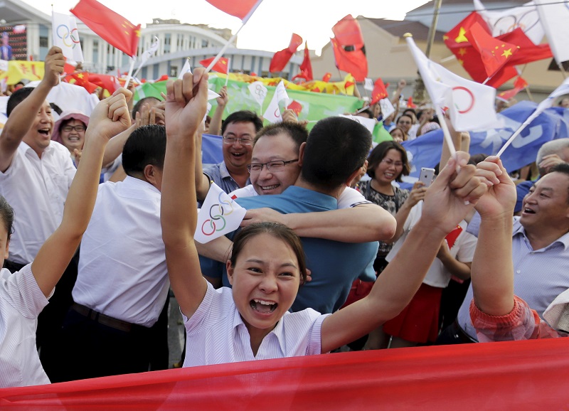 中國北京31日取得2022冬奧主辦權，市民高興地揮舞著中國國旗與申奧標誌。圖片來源：達志影像/路透社   