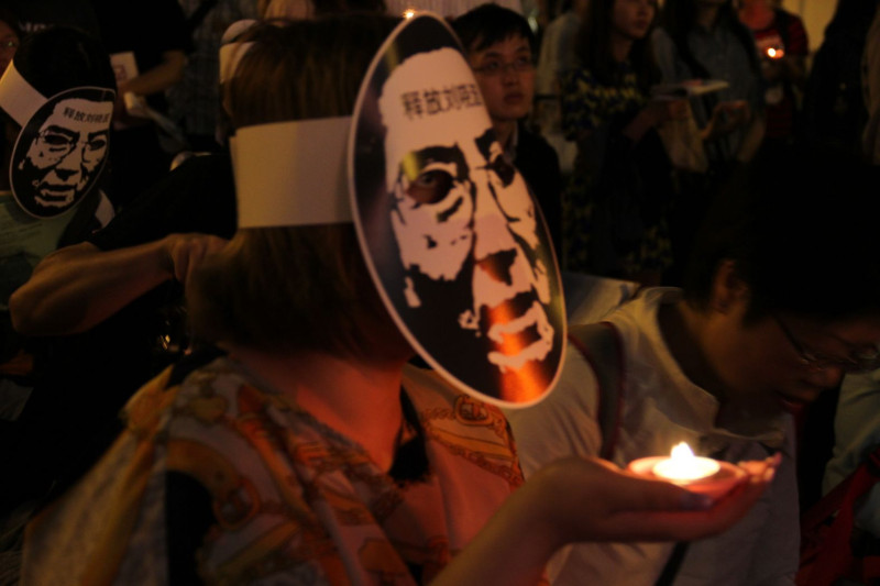 中國維權人士陳光誠今（4）晚透過音帶的方式，跨海聲援在中正紀念堂自由廣場舉辦的「六四X二十四晚會」，民眾戴起劉曉波的面具、手捧蠟燭，表達弔念之意。圖：周思宇/攝   