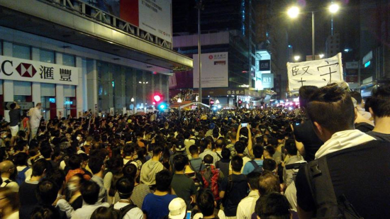 港警今(19)天凌晨以警棍驅離佔中民眾打人，示威者被迫退後，凌晨零時35分，警方和民眾在亞皆老街及彌敦道交界對峙。圖：翻攝「香港獨立媒體網」官方臉書   