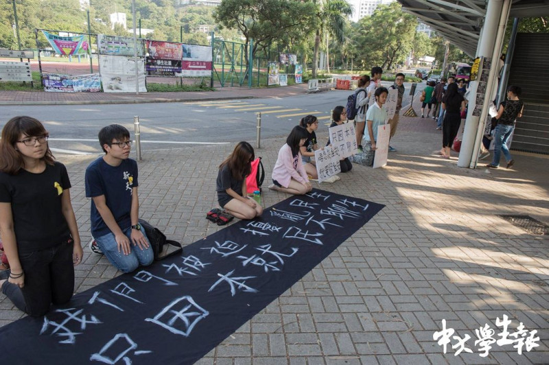 6日上午，一群支持罷課及佔領行動的學生排成一條線，在火車站廣場手持「我們被迫影響民生，只因本就民不聊生」標語，向同學下跪，希望學生繼續罷課聲援佔中。圖：翻攝香港專上學生聯會臉書   