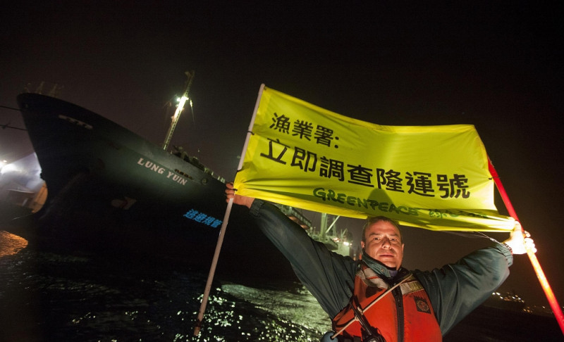綠色和平行動成員在高雄港灣對涉嫌非法運作運搬船「隆運號」投射影像，並在海上舉起「漁業署：立即調查隆運號」布條抗議。圖片來源：綠色和平組織   