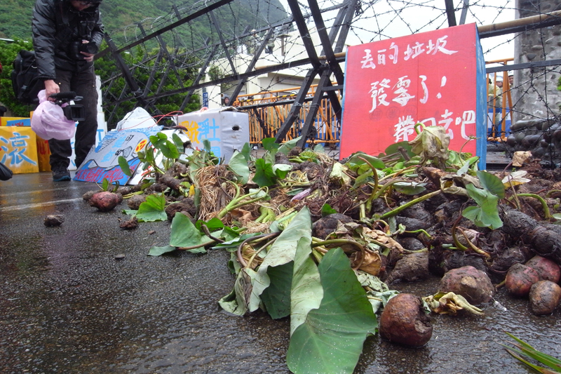 族人浩浩蕩蕩在上午9時30分在貯存場前會師集結，他們在警方拒馬前堆置自己種的芋頭和地瓜，痛批核廢料外洩導致作物生長異常、腐爛。圖片來源：楊宗興/攝&nbsp;&nbsp;&nbsp;