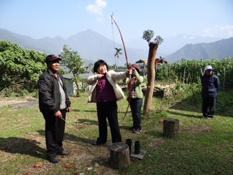屏科大森林系副教授陳美惠（拉引者)經常穿梭往來社區部落間，對體驗部落文化興緻濃厚，連部落提供旅遊把玩的弓箭，陳美惠都要親身感受一下。圖：屏科大社區林業研究室提供   