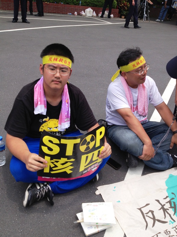 立法院今（2）日正午時分，公投護台灣聯盟在鐵門外推擠、與警方僵持不下時，立法院中庭居然迸出一個非常年輕的男孩，手拿鮮黃色字樣的反核標誌，身旁是他進場以後，前來陪同、關心的一位立委助理。圖：王立柔/攝   